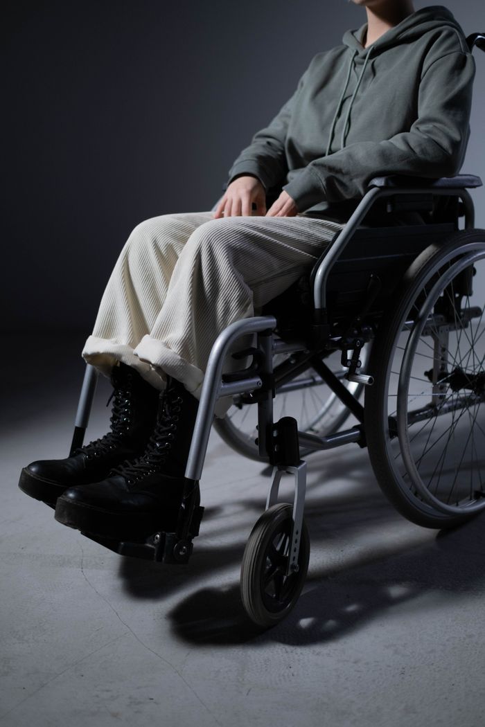 An individual seated in a wheelchair dressed casually indoors, focusing on mobility and independence.